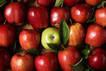 Fresh ripe apples with leaves on wooden table, flat lay