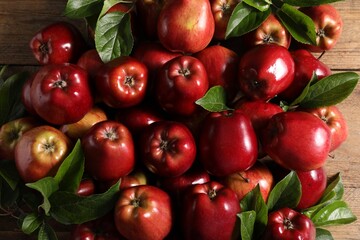 Fresh ripe red apples with leaves on wooden table, flat lay