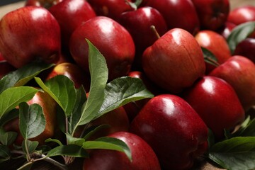 Fresh ripe red apples with leaves as background, closeup