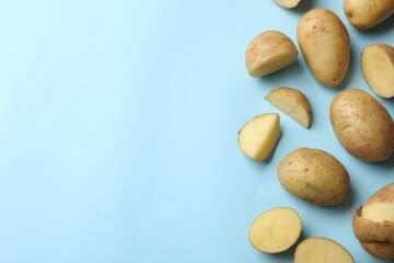 Fresh raw potatoes on light blue background, flat lay. Space for text