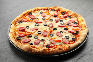 Tasty pizza with cheese, dry smoked sausages, olives and pepper on grey table