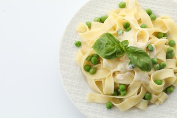 Delicious pasta with green peas, fresh basil and creamy sauce isolated on white, top view