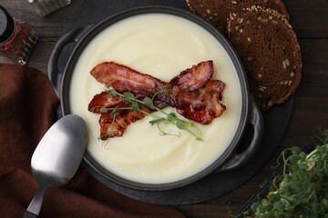Delicious potato soup with bacon and microgreens in bowl served on wooden table, flat lay