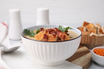 Delicious lentil soup with bacon and parsley in bowl on table