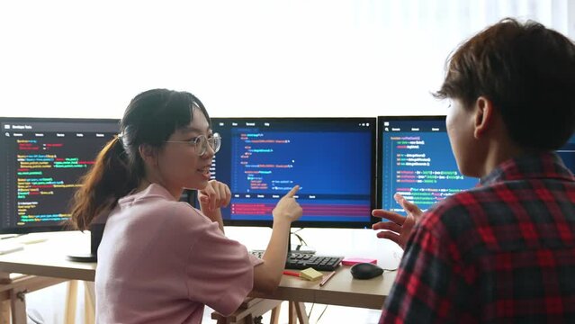 Slow motion back end software developer engineer for computer programming working together on debugging writing computing code, solving complex algorithms display on monitor in office. Burgeoning
