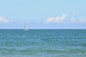 Small sailing boat with crew sailing in the middle of the ocean