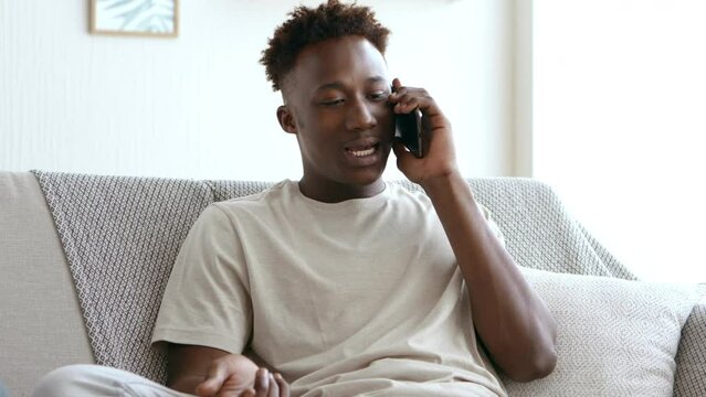 Breakup. Upset african guy emotionally talking with his ex girlfriend by phone at home