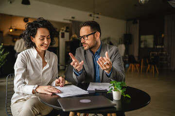 Man and woman colleagues hold documents and work together at cafe