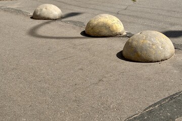 Yellow restrictive hemispheres on the asphalt road in the parking area of the car and the pedestrian area of walking people at the street. Area for foot people