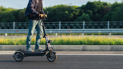 A man on a scooter is riding along the road at high speed © pavelkant