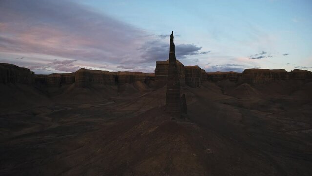 Aerial turning view of pinnacle rock formation in desert at sunset / Caineville, Utah, United States