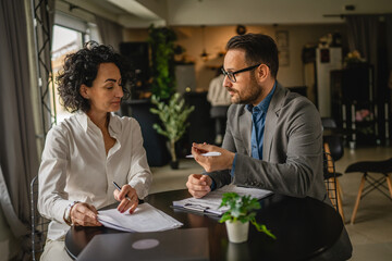 Man and woman colleagues hold documents and work together at cafe