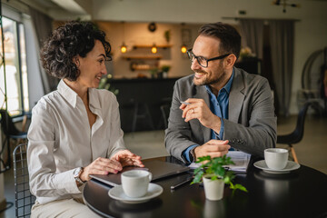 Two colleagues man and woman on break at cafe drink coffee and talk