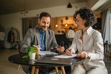 Man and woman colleagues hold documents and work together at cafe