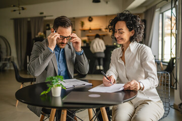 Man and woman colleagues hold documents and work together at cafe