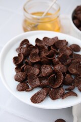 Breakfast cereal. Chocolate corn flakes and milk in bowl on white tiled table, closeup
