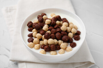 Breakfast cereal. Tasty corn balls with milk in bowl on white textured table, closeup