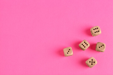 Many wooden game dices on pink background, flat lay. Space for text