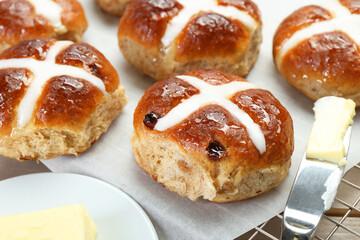 Tasty hot cross buns and knife with butter on table, closeup