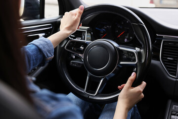 Woman holding steering wheel while driving her car, closeup