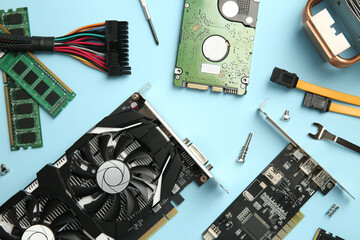 Graphics card and other computer hardware on light blue background, flat lay