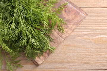 Board with sprigs of fresh dill on wooden table, top view. Space for text