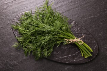 Bunch of fresh dill on dark textured table, above view