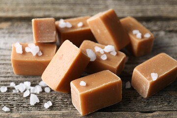 Yummy caramel candies with sea salt on wooden table, closeup