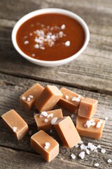 Yummy caramel candies with sea salt on wooden table, closeup