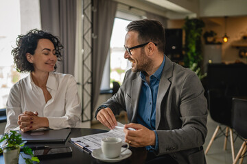 Man and woman on break at cafe drink coffee check list on clipboard