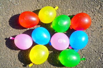膨らませた沢山のカラフルな水風船。小学生の子供の夏休みの外遊び。