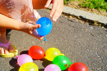 外で水風船遊びをしている小学生の子ども。夏休みの外遊び。