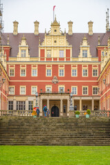 Naklejka premium The front view of Chateau Bad Muskau, with visitors on the entrance steps, under a grey, overcast sky. Saxony, Germany