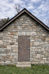 stone building with wooden door (antique retro vintage) historic pump station sign in park