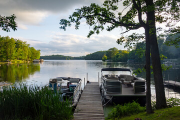 Looking out onto a Wisconsin northwoods lake as the last rays of sunlight begin to fade.  Many pontoon boats have returned from fishing for the evening.