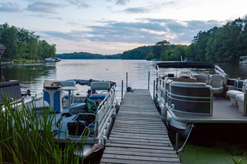 Looking out onto a Wisconsin northwoods lake as the last rays of sunlight begin to fade.  Many pontoon boats have returned from fishing for the evening. © Jennifer