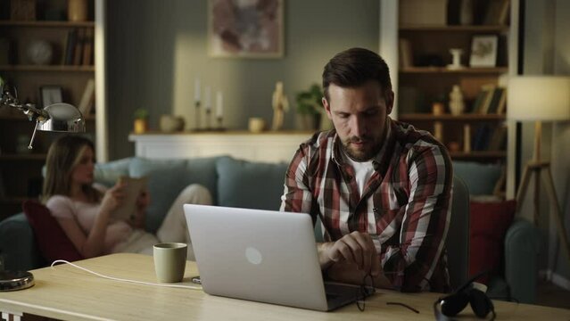 Exhausted freelancer at desk working with laptop, overworked guy suffer from eyestrain eyes pain, take off glasses and takes a break 