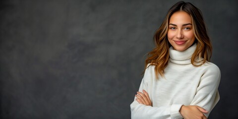 Smiling Young Woman with Wavy Brown Hair Wearing White Turtleneck Sweater Standing with Crossed Arms Against Dark Gray Background