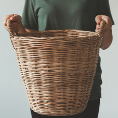 A cropped image of a beautiful young woman holding a laundry basket of clothes with a white background.