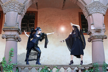 Zwei Frauen als Hexen verkleidet kämpfen mit einem Lichtball