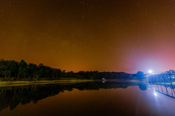 star natural background At night, the Milky Way can be clearly seen with the naked eye, with the blur of light hitting the water surface and the cool, humid air.
