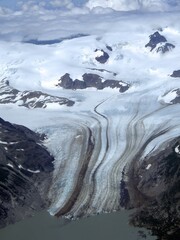 view of tidewater glacier and snowy mountain peaks  on a sunny summer day while flying to chinitna...