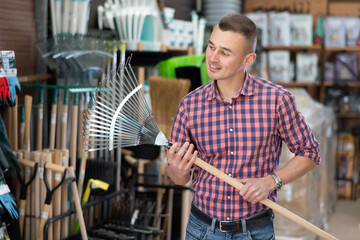 Male gardener choosing rake in a hardware store