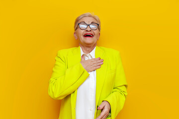 old businesswoman in glasses and business clothes scoff and smiling on a yellow isolated...