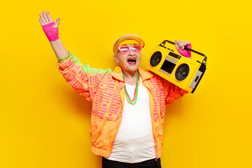 funny crazy granny in hipster clothes listening to music on tape recorder and singing on yellow...