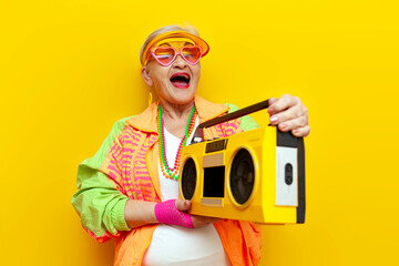 funny crazy granny in hipster clothes listening to music on tape recorder and singing on yellow...