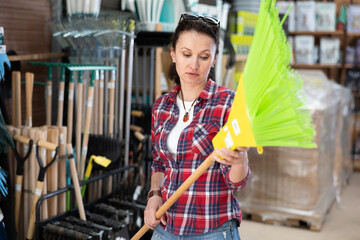 Woman shopping at hardware store - choosing a broom