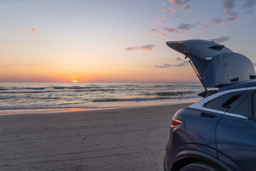 Hatchback trunk open against a background of sunset over sea