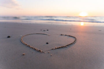 Hearth symbol on sand against a background of sunset over the sea