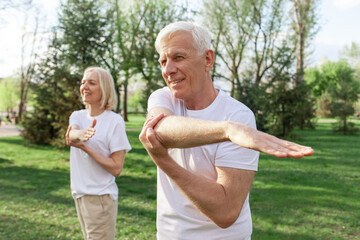 elderly couple of seniors man and woman doing exercises and training in the park outdoors,...